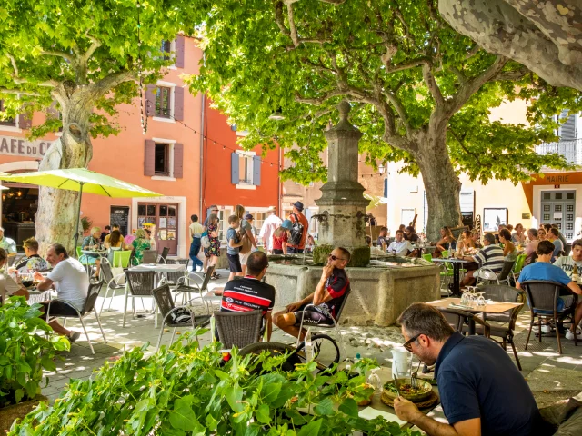 Place centrale du village de Villedieu avec des personnes qui se restaurent